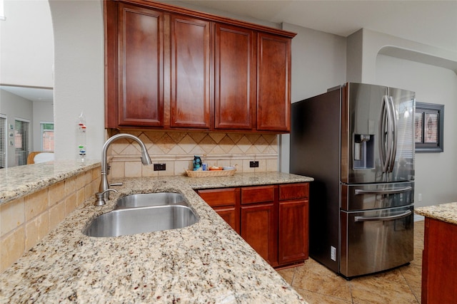 4953 Van Zandt Dr, Fort Worth, TX 76244 - kitchen with a sink, stainless steel fridge, tasteful backsplash, light stone counters, and reddish brown cabinets