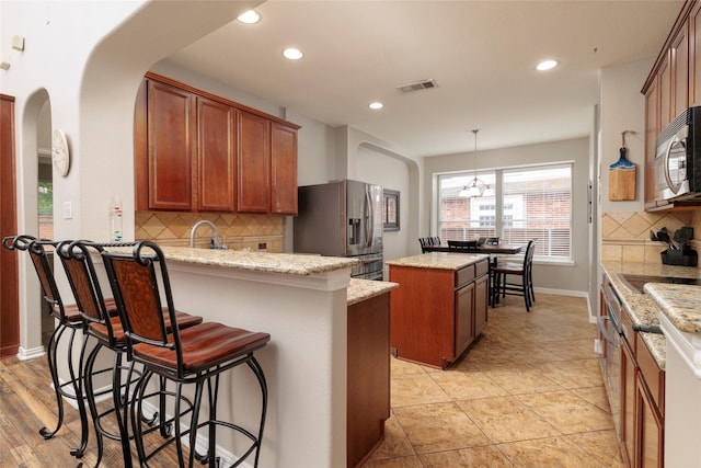 4953 Van Zandt Dr, Fort Worth, TX 76244 - kitchen featuring tasteful backsplash, arched walkways, recessed lighting, appliances with stainless steel finishes, and a kitchen island
