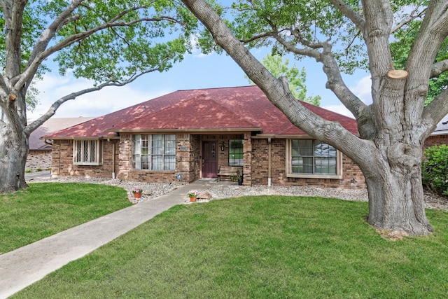 single story home featuring brick siding, a shingled roof, and a front lawn