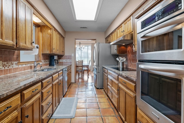 kitchen with visible vents, decorative backsplash, under cabinet range hood, a sink, and stainless steel appliances