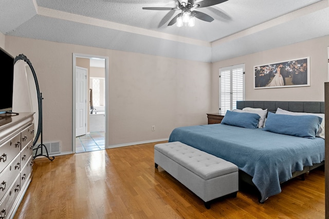 bedroom featuring visible vents, light wood-style floors, baseboards, a textured ceiling, and connected bathroom