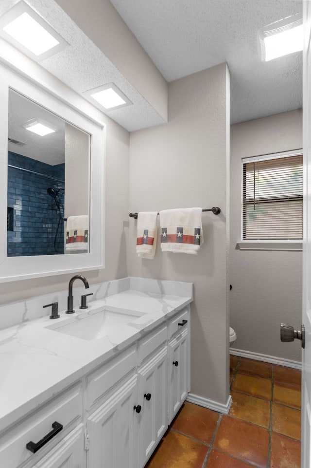 bathroom with vanity, toilet, tile patterned floors, a textured ceiling, and baseboards