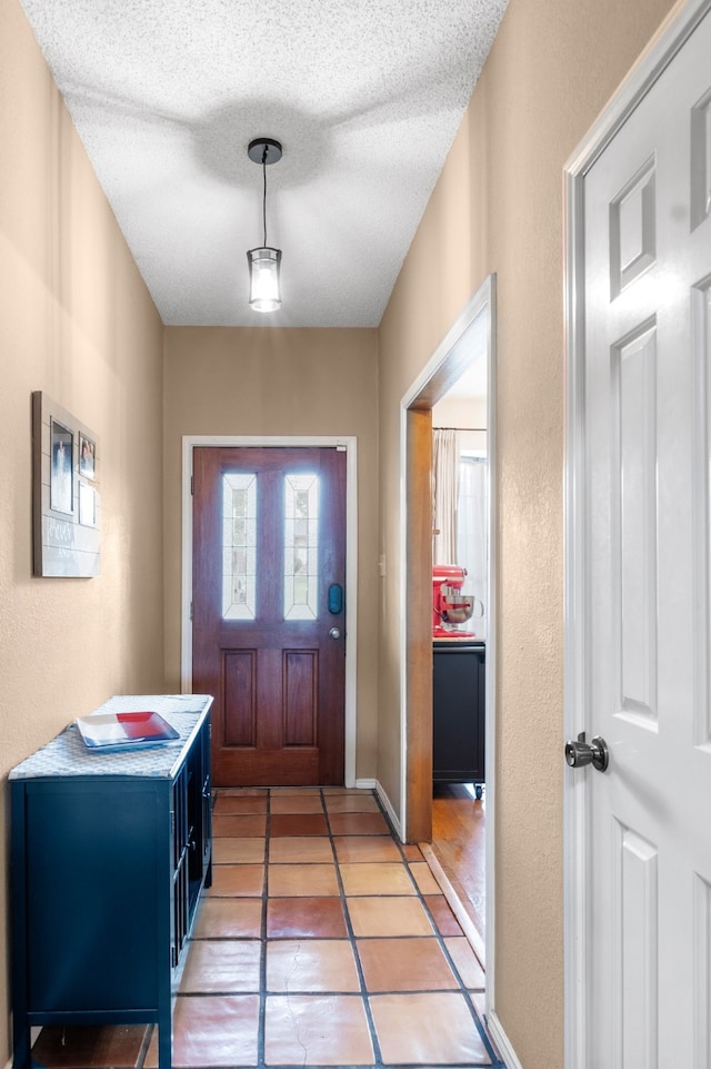 entryway with a textured ceiling, a textured wall, and light tile patterned flooring