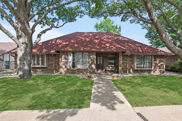 single story home with brick siding, a shingled roof, and a front lawn