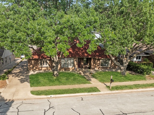 obstructed view of property with brick siding and a front yard