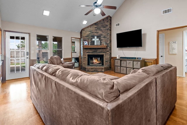 living area with visible vents, a brick fireplace, ceiling fan, and high vaulted ceiling