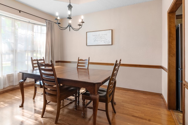 dining room featuring baseboards, a chandelier, and light wood-type flooring