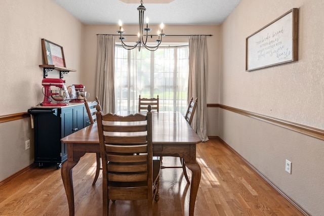dining space featuring baseboards, a chandelier, and light wood-type flooring