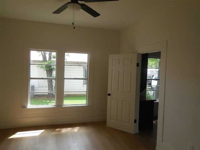 empty room featuring wood finished floors, a ceiling fan, and baseboards