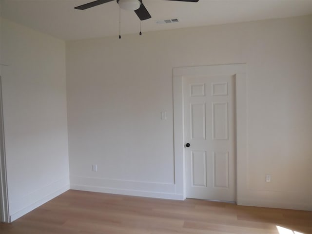 empty room with baseboards, visible vents, ceiling fan, and light wood-type flooring