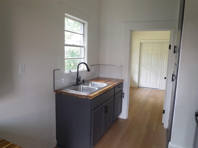 kitchen featuring wooden counters, a sink, tasteful backsplash, and light wood-type flooring