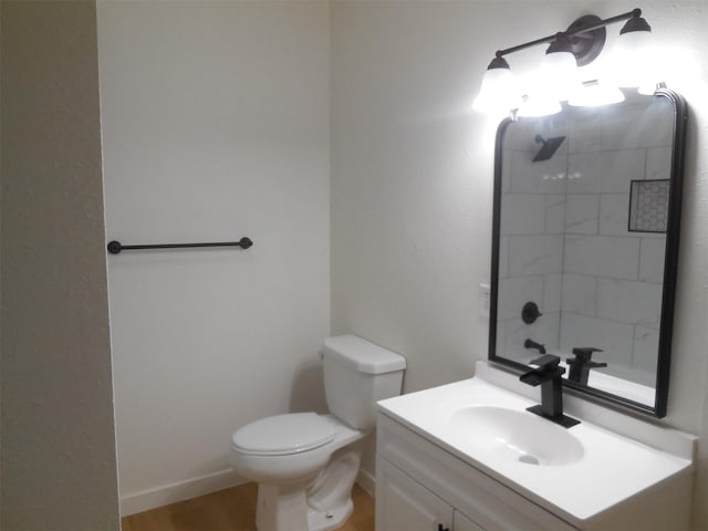 bathroom with wood finished floors, tiled shower, toilet, vanity, and baseboards