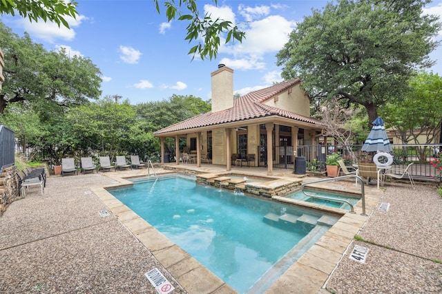 view of swimming pool featuring fence, cooling unit, a patio, and a pool with connected hot tub