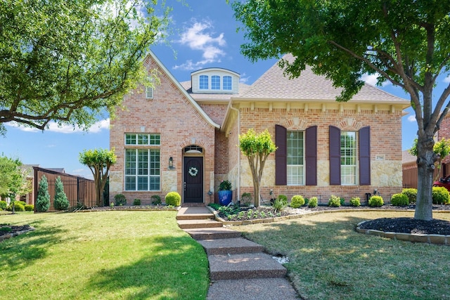 view of front of property with fence, a front lawn, a shingled roof, and brick siding