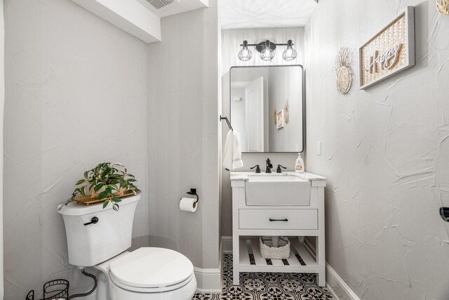 half bathroom with baseboards, toilet, tile patterned flooring, and vanity