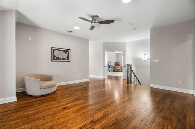 unfurnished room with wood finished floors, an upstairs landing, baseboards, visible vents, and a ceiling fan