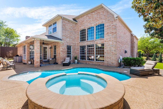 view of swimming pool featuring fence, ceiling fan, a pool with connected hot tub, and a patio area