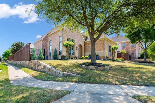 view of front of home featuring brick siding, fence, and a front yard