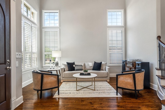 living area featuring a towering ceiling, wood finished floors, and baseboards