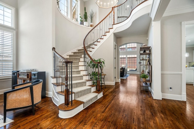 foyer with arched walkways, wood finished floors, and baseboards