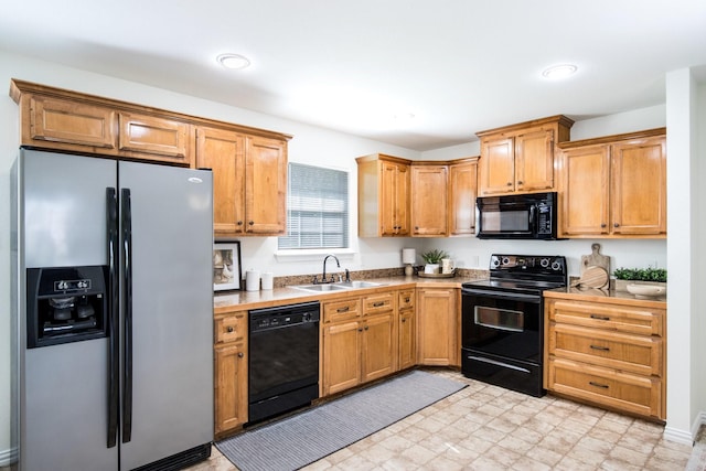 kitchen with recessed lighting, black appliances, light countertops, and a sink