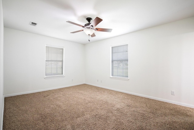unfurnished room featuring a ceiling fan, visible vents, a wealth of natural light, and carpet