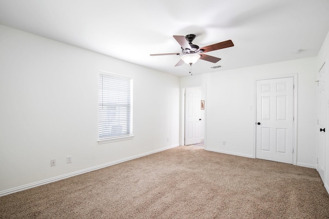 carpeted empty room with visible vents, ceiling fan, and baseboards