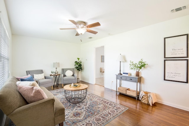 living area with baseboards, visible vents, wood finished floors, and ceiling fan
