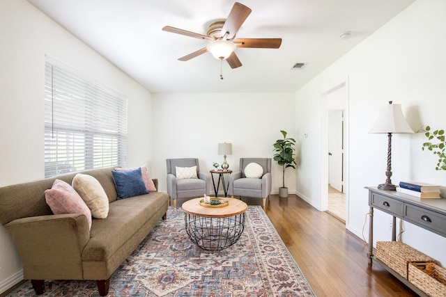 living area featuring wood finished floors, visible vents, a ceiling fan, and baseboards