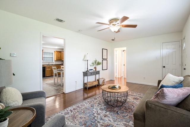 living area with wood finished floors, a ceiling fan, visible vents, and baseboards