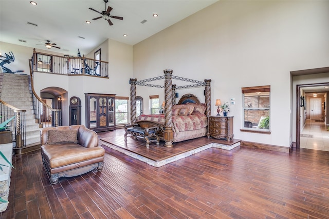 bedroom with high vaulted ceiling, visible vents, baseboards, arched walkways, and wood finished floors