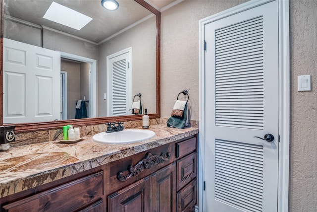 bathroom with crown molding, a skylight, a textured wall, and vanity