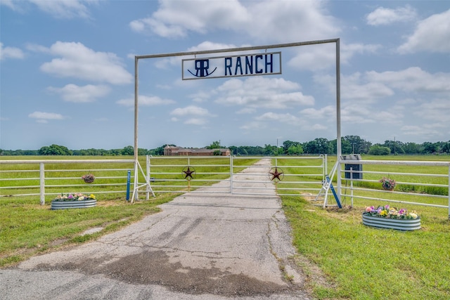 view of street with a rural view, a gated entry, and aphalt driveway
