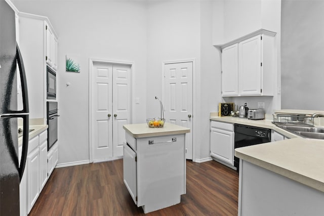 kitchen featuring black appliances, dark wood-style flooring, a towering ceiling, and a center island