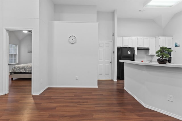 kitchen featuring white cabinetry, light countertops, freestanding refrigerator, under cabinet range hood, and dark wood-type flooring