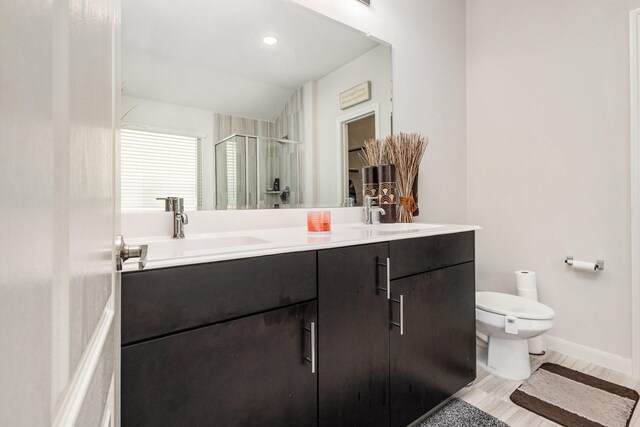 full bathroom featuring double vanity, a sink, a stall shower, and toilet