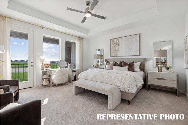 bedroom featuring access to exterior, a ceiling fan, light colored carpet, and a tray ceiling