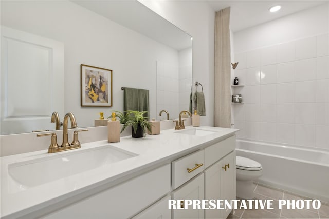 bathroom featuring toilet, double vanity, a sink, and tile patterned floors