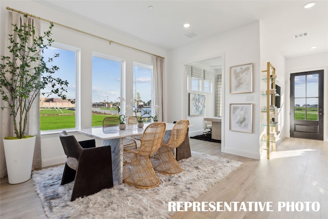 dining room featuring baseboards, visible vents, light wood-style floors, and plenty of natural light