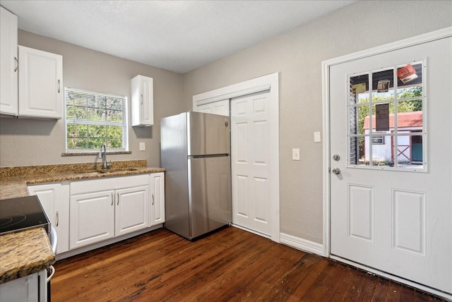 kitchen featuring freestanding refrigerator, electric range oven, dark wood-style flooring, a sink, and white cabinetry