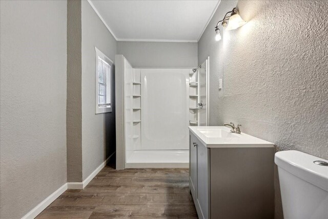 full bathroom with crown molding, a textured wall, a stall shower, wood finished floors, and vanity