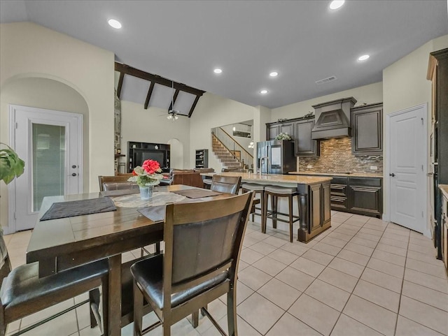 dining space with light tile patterned floors, lofted ceiling, stairway, and ceiling fan
