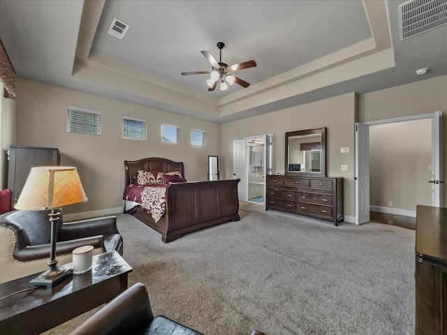 carpeted bedroom featuring visible vents, baseboards, and a tray ceiling