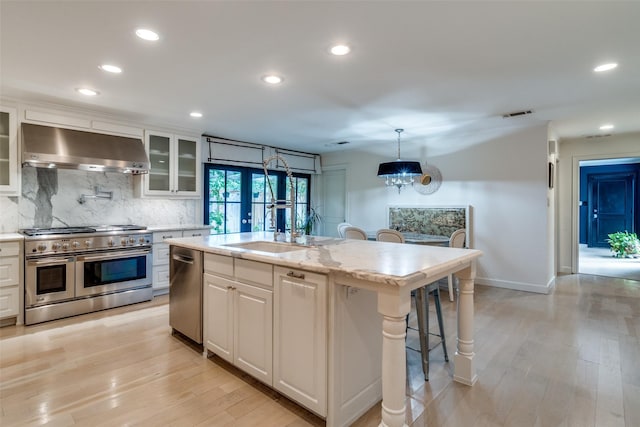 kitchen with recessed lighting, wall chimney exhaust hood, white cabinetry, appliances with stainless steel finishes, and backsplash