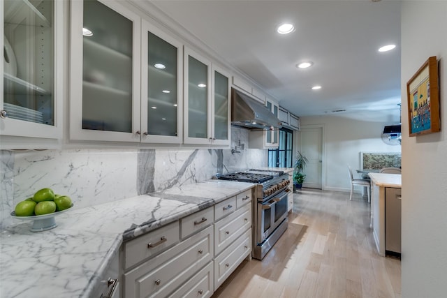 kitchen featuring exhaust hood, appliances with stainless steel finishes, light stone countertops, recessed lighting, and white cabinetry