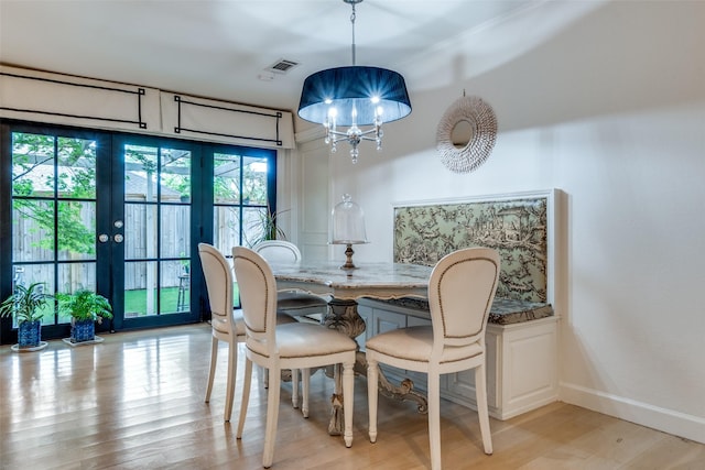 dining room with french doors, visible vents, light wood-type flooring, baseboards, and a notable chandelier