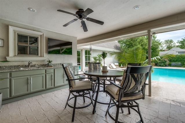 view of patio / terrace featuring a ceiling fan, outdoor dining space, exterior kitchen, an outdoor pool, and a sink