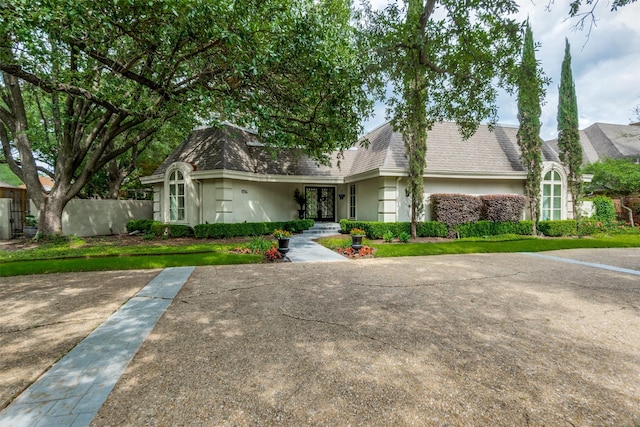 view of front of property with roof with shingles, stucco siding, and mansard roof