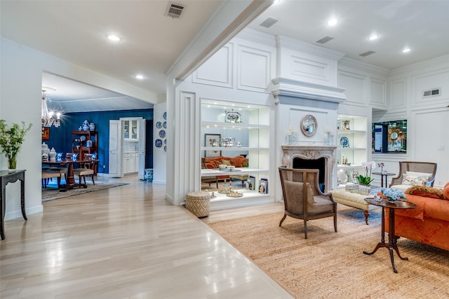 living room featuring crown molding, an inviting chandelier, light wood-style floors, and visible vents