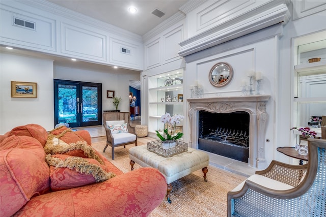living room with visible vents, built in shelves, and a high end fireplace
